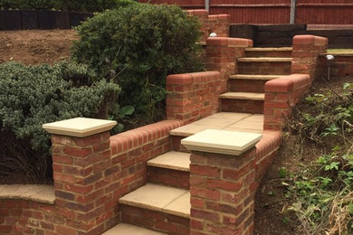 Design ideas for a medium sized sloped formal full sun garden for spring in Other with a retaining wall and brick paving.