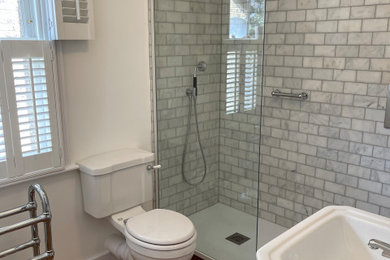 Example of a classic gray tile and marble tile single-sink bathroom design in London with a two-piece toilet, white walls and a console sink