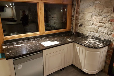This is an example of a classic kitchen in West Midlands with granite worktops and glass sheet splashback.