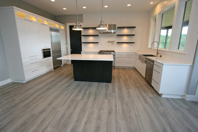 Example of a mid-sized trendy u-shaped gray floor and vinyl floor open concept kitchen design in Seattle with a farmhouse sink, flat-panel cabinets, yellow cabinets, quartz countertops, white backsplash, mosaic tile backsplash, stainless steel appliances, an island and white countertops
