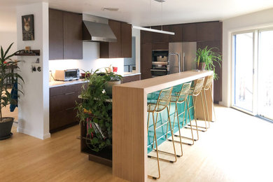 Kitchen - modern kitchen idea in Philadelphia with flat-panel cabinets, dark wood cabinets, quartz countertops, white backsplash, stainless steel appliances and white countertops