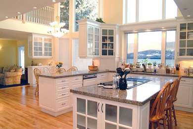 Inspiration for a mid-sized timeless l-shaped medium tone wood floor and beige floor enclosed kitchen remodel in Calgary with a double-bowl sink, white cabinets, granite countertops, beige backsplash, cement tile backsplash, stainless steel appliances and an island