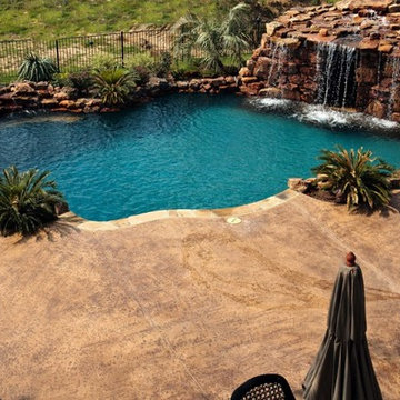 Lagoon style swimming pool with waterfall grotto with spa inside.