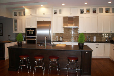 Inspiration for a large transitional u-shaped medium tone wood floor eat-in kitchen remodel in New York with an undermount sink, recessed-panel cabinets, white cabinets, solid surface countertops, beige backsplash, glass tile backsplash, stainless steel appliances and an island