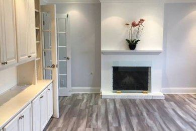 Example of a large transitional formal and open concept medium tone wood floor and brown floor living room design in Los Angeles with gray walls, a standard fireplace, a brick fireplace and no tv