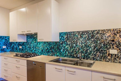 This is an example of a tropical kitchen in Sydney with blue splashback and glass sheet splashback.