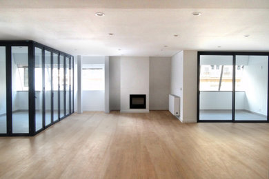 Modelo de salón cerrado y beige y blanco minimalista grande con suelo de madera en tonos medios, chimenea lineal, marco de chimenea de metal y suelo marrón