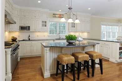 Inspiration for a large timeless u-shaped dark wood floor and brown floor eat-in kitchen remodel in New York with an undermount sink, raised-panel cabinets, black cabinets, white backsplash, subway tile backsplash, stainless steel appliances and an island