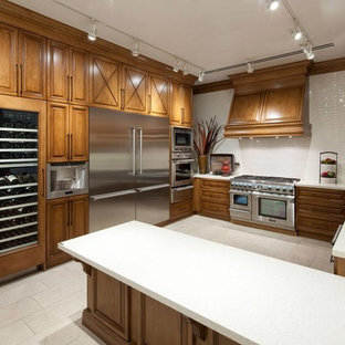 Kitchen pantry designs - Inspiration for a l-shaped kitchen pantry remodel in Jackson with a drop-in sink, raised-panel cabinets, medium tone wood cabinets, solid surface countertops, white backsplash, subway tile backsplash, stainless steel appliances and an island