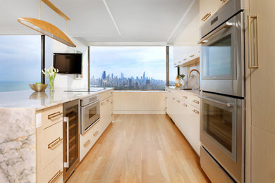 Inspiration for a mid-sized modern galley light wood floor and beige floor eat-in kitchen remodel in Chicago with flat-panel cabinets, white cabinets, quartzite countertops, an island, a single-bowl sink, yellow backsplash, stone slab backsplash, stainless steel appliances and white countertops