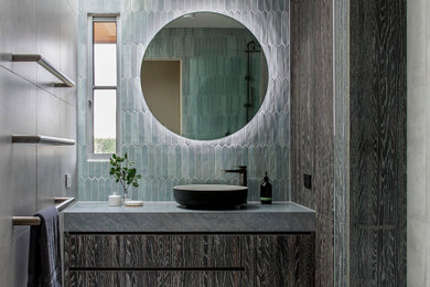 Mid-sized modern 3/4 bathroom in Melbourne with flat-panel cabinets, dark wood cabinets, an alcove shower, a wall-mount toilet, gray tile, grey walls, a vessel sink, grey floor, a hinged shower door, grey benchtops, a single vanity, a built-in vanity, coffered and decorative wall panelling.