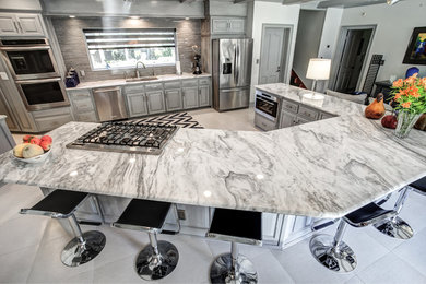 Open concept kitchen - large eclectic single-wall porcelain tile open concept kitchen idea in Miami with raised-panel cabinets, gray cabinets, marble countertops, gray backsplash, matchstick tile backsplash, stainless steel appliances, an island and an undermount sink