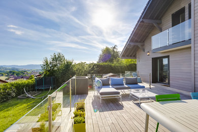 Aménagement d'une terrasse latérale et au premier étage moderne avec aucune couverture et un garde-corps en verre.
