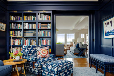 Beach style open concept medium tone wood floor, brown floor and wall paneling living room library photo in Boston with blue walls and no tv