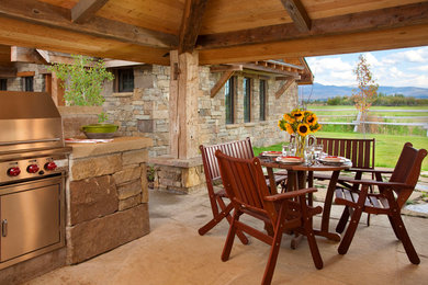 Example of a large farmhouse backyard stone patio kitchen design in Other with a pergola