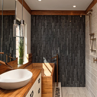 Aménagement d'une salle de bain principale asiatique de taille moyenne avec des portes de placard blanches, un bain japonais, un WC à poser, un sol en carrelage de porcelaine, une vasque, un plan de toilette en bois, un placard à porte plane, une douche ouverte, un carrelage noir, un carrelage de pierre, un mur beige et un plan de toilette marron.