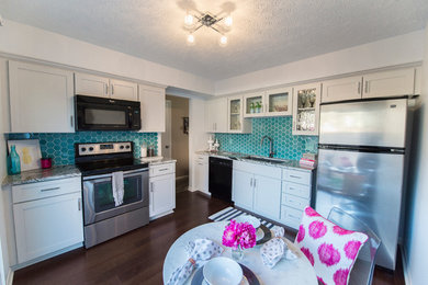 Example of a small eclectic l-shaped dark wood floor enclosed kitchen design in Omaha with an undermount sink, shaker cabinets, gray cabinets, granite countertops, blue backsplash, glass tile backsplash, stainless steel appliances and no island