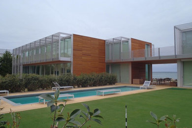 Pool house - large modern backyard rectangular lap pool house idea in New York with decking