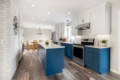 Large transitional galley vinyl floor and brown floor eat-in kitchen photo in Minneapolis with an undermount sink, shaker cabinets, blue cabinets, quartz countertops, white backsplash, ceramic backsplash, stainless steel appliances, an island and white countertops