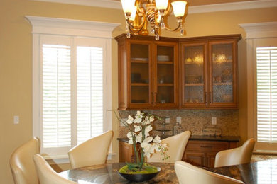 Example of a mid-sized classic u-shaped medium tone wood floor eat-in kitchen design in Indianapolis with a drop-in sink, raised-panel cabinets, medium tone wood cabinets, granite countertops, beige backsplash, mosaic tile backsplash, stainless steel appliances and an island