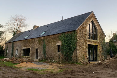 Réalisation d'une grande façade de maison en pierre à un étage avec un toit à deux pans.