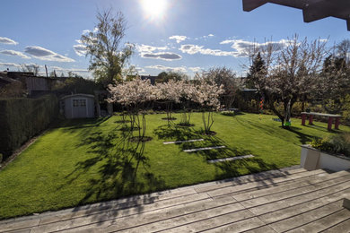 Geometrischer Moderner Garten im Sommer, hinter dem Haus mit Blumenbeet, direkter Sonneneinstrahlung und Dielen in Sonstige