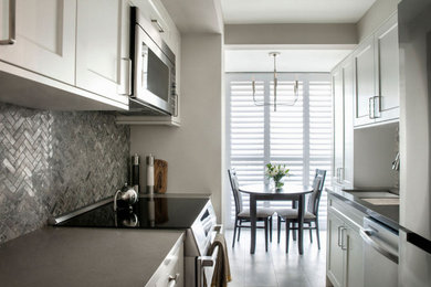 Galley porcelain tile and gray floor kitchen photo in Toronto with raised-panel cabinets, white cabinets, quartz countertops, gray backsplash, marble backsplash, stainless steel appliances, no island, gray countertops and an undermount sink
