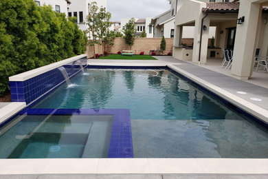 Imagen de piscina alargada tradicional renovada de tamaño medio rectangular en patio trasero con losas de hormigón y paisajismo de piscina