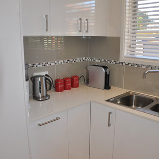 Mid-sized modern kitchen pantry appliance - Mid-sized minimalist u-shaped light wood floor kitchen pantry photo in Canberra - Queanbeyan with a drop-in sink, white cabinets, quartz countertops, gray backsplash, mosaic tile backsplash, stainless steel appliances, an island and flat-panel cabinets