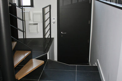 Aménagement d'un hall d'entrée contemporain de taille moyenne avec un mur blanc, un sol en carrelage de céramique, une porte simple, une porte noire et un sol noir.
