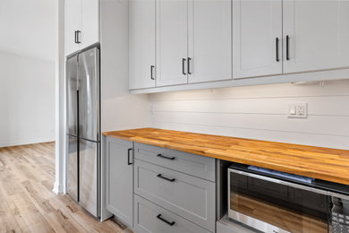 Mid-sized single-wall dark wood floor and brown floor eat-in kitchen photo in DC Metro with an undermount sink, shaker cabinets, white cabinets, wood countertops, white backsplash, ceramic backsplash and stainless steel appliances
