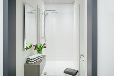 Mittelgroßes Modernes Duschbad mit flächenbündigen Schrankfronten, grauen Schränken, bodengleicher Dusche, Wandtoilette, weißen Fliesen, Porzellanfliesen, weißer Wandfarbe, Porzellan-Bodenfliesen, Aufsatzwaschbecken, Waschtisch aus Holz, grauem Boden und offener Dusche in Köln
