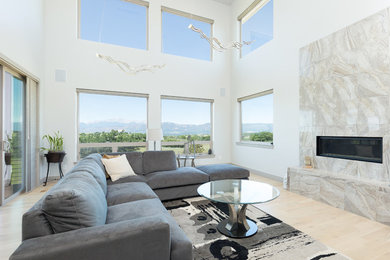 Photo of a modern open concept family room in Denver with white walls, light hardwood floors, a ribbon fireplace and a tile fireplace surround.