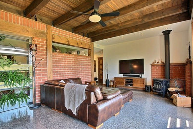 Family room - mid-sized contemporary enclosed concrete floor and gray floor family room idea in Montreal with white walls, a wood stove, a brick fireplace and a wall-mounted tv