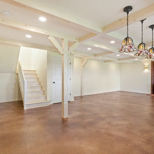 Diseño de sótano con puerta rural, grande, con paredes blancas, suelo de cemento, estufa de leña, marco de chimenea de ladrillo y suelo marrón