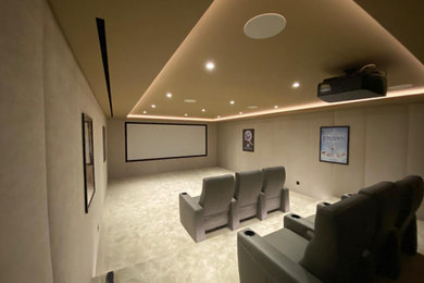 Inspiration for a large contemporary enclosed home cinema in Other with beige walls, carpet, a projector screen and grey floors.