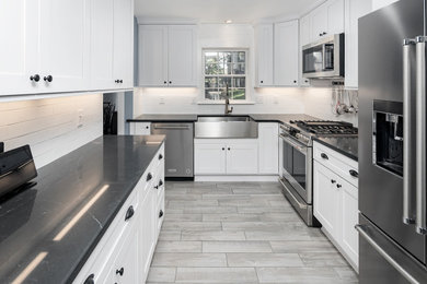 Example of a small transitional u-shaped kitchen design in Charlotte with a farmhouse sink, recessed-panel cabinets, quartz countertops, subway tile backsplash and stainless steel appliances