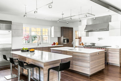 Kitchen - large contemporary brown floor and dark wood floor kitchen idea in Boston with an undermount sink, flat-panel cabinets, white backsplash, stainless steel appliances, two islands and light wood cabinets