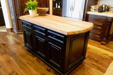 Kitchen - kitchen idea in Seattle with raised-panel cabinets, wood countertops and an island