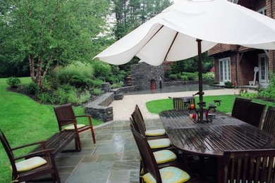 This is an example of a large transitional backyard patio in New York with with fireplace, tile and no cover.