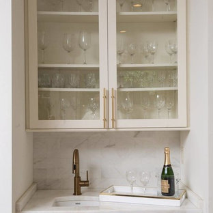 ニューオリンズの小さいコンテンポラリースタイルのおしゃれなウェットバー (アンダーカウンターシンク、ガラス扉のキャビネット、白いキャビネット、大理石カウンター、グレーのキッチンパネル、大理石の床) の写真