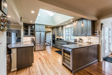 Mid-sized elegant u-shaped medium tone wood floor and brown floor eat-in kitchen photo in Denver with an undermount sink, shaker cabinets, medium tone wood cabinets, granite countertops, white backsplash, ceramic backsplash, white appliances, a peninsula and gray countertops