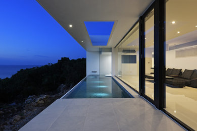 Imagen de piscina infinita moderna pequeña rectangular con suelo de baldosas