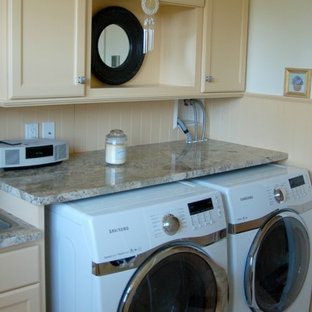 ボストンの中サイズのビーチスタイルのおしゃれな家事室 (ドロップインシンク、落し込みパネル扉のキャビネット、黄色いキャビネット、御影石カウンター、白い壁、左右配置の洗濯機・乾燥機、黄色い床) の写真