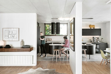 Photo of a large midcentury l-shaped open plan kitchen in Melbourne with white splashback, subway tile splashback, flat-panel cabinets, black cabinets, with island and grey floor.