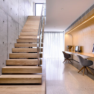 Modern home office and library in Melbourne with brown walls, a built-in desk and white floors.