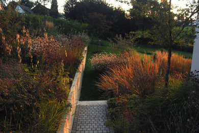 Diseño de jardín de secano actual grande en verano con exposición total al sol, adoquines de piedra natural y parterre de flores