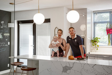 Mid-sized trendy l-shaped laminate floor and gray floor eat-in kitchen photo in Vancouver with a drop-in sink, flat-panel cabinets, gray cabinets, quartzite countertops, white backsplash, stone slab backsplash, stainless steel appliances, an island and white countertops