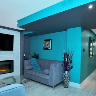 Traditional look-out basement in Toronto with multi-coloured walls, laminate floors, a standard fireplace, a stone fireplace surround and grey floors.
