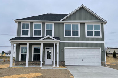 Example of a large classic green two-story vinyl and board and batten house exterior design in Other